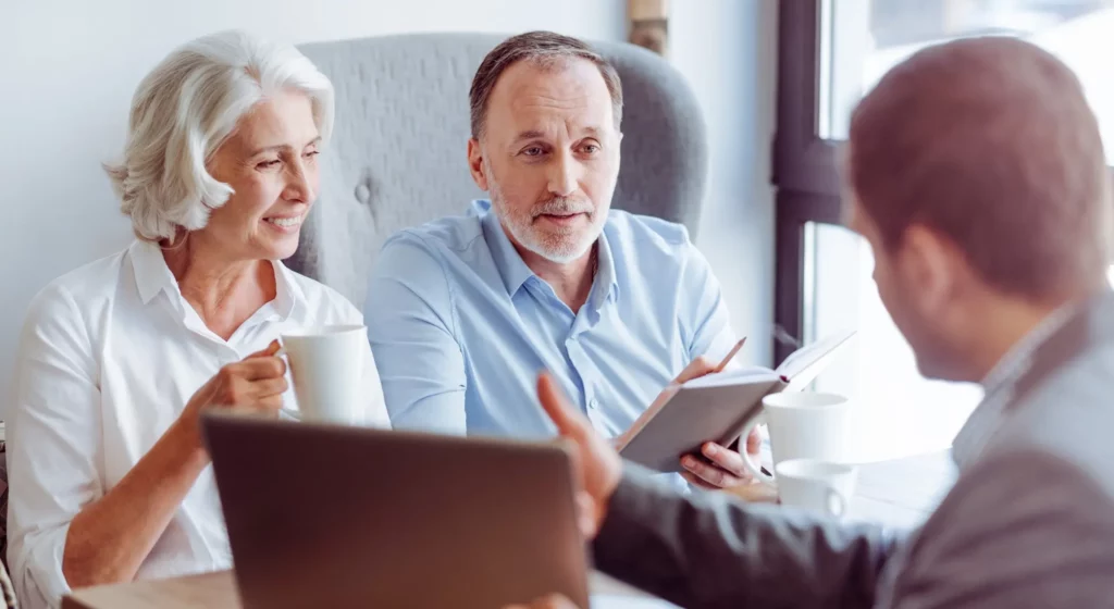 Couple senior discutant de documents avec un conseiller funéraire lors d'une réunion.